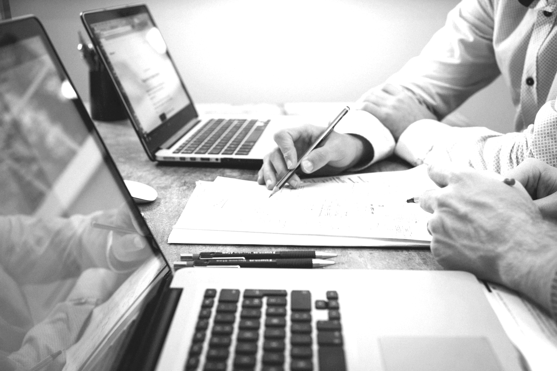 person holding pencil near laptop computer